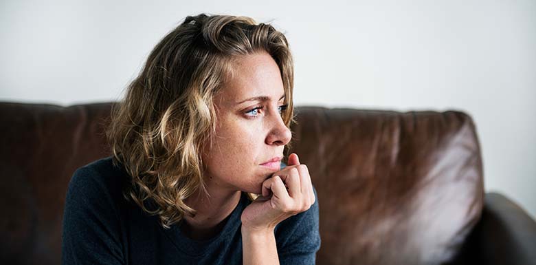 Woman looking worried on a sofa