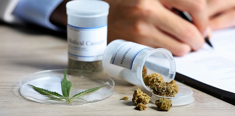Two bottles of medical marijuana on a table with doctor writing paperwork